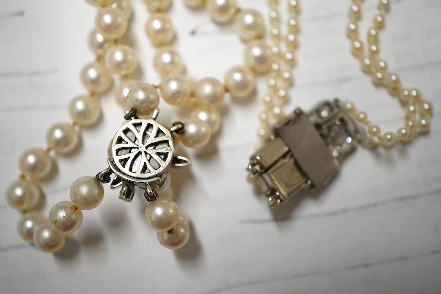 Two double strand cultured pearl necklaces, one graduated with paste set white metal clasp, 48cm, the other with cultured pearl set 9ct white gold clasp.